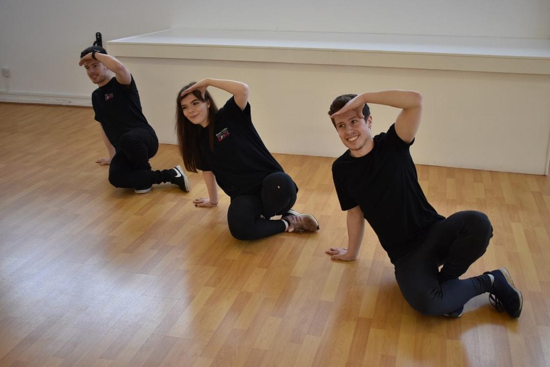 3 people on the dance studio floor in a dance pose