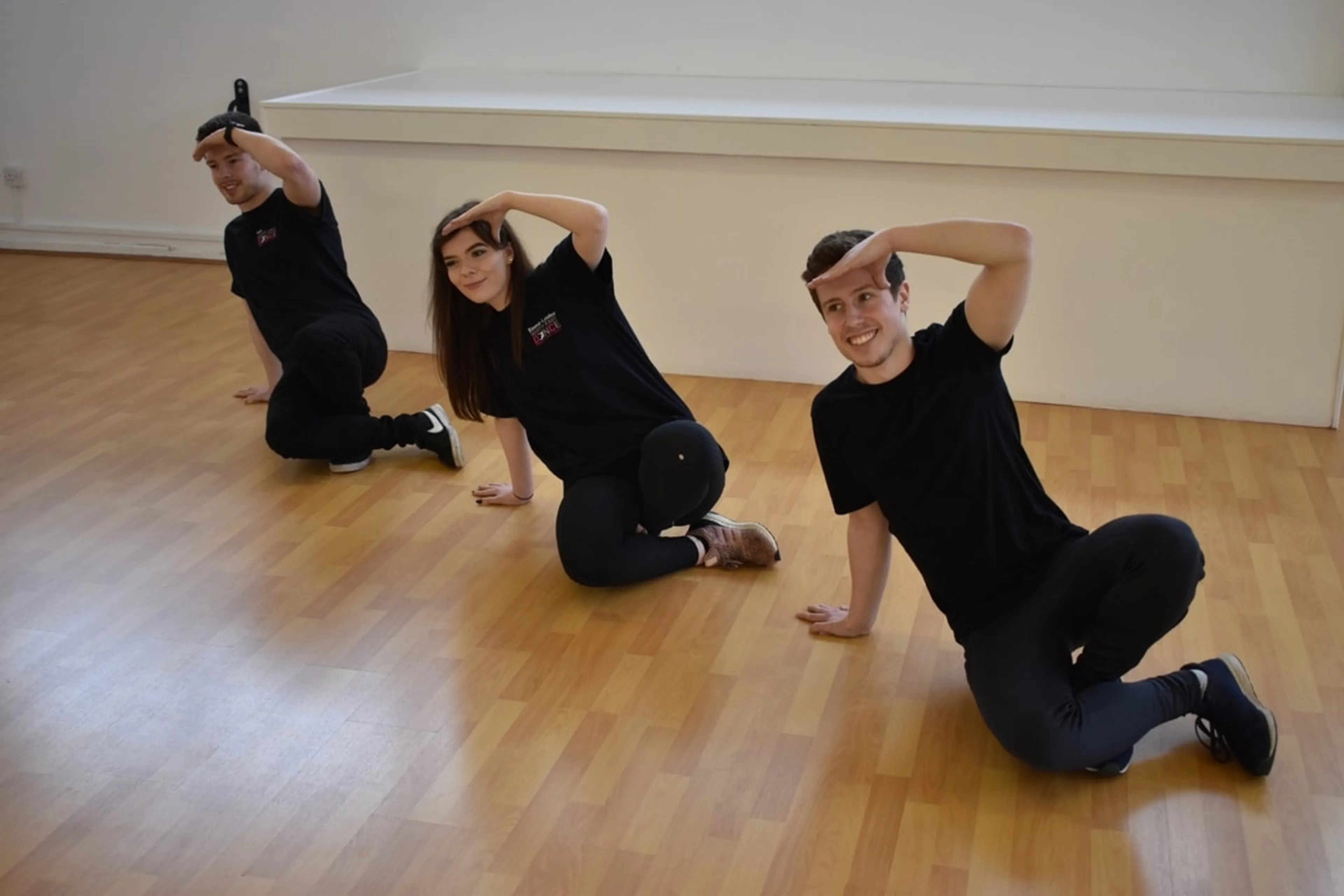 3 people on the dance studio floor in a dance pose